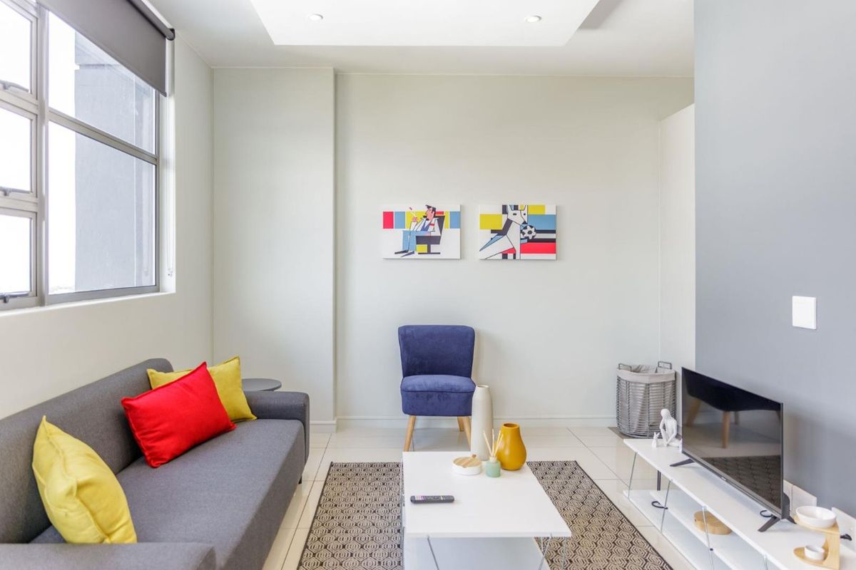 A bright and modern living room featuring neutral walls, tiled flooring, and recessed ceiling lighting, offering a clean and contemporary living space.