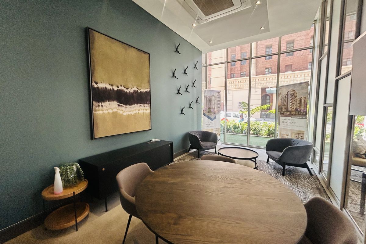 A modern, well-lit living area featuring floor-to-ceiling windows, recessed ceiling lighting, and a built-in ceiling air conditioning unit.