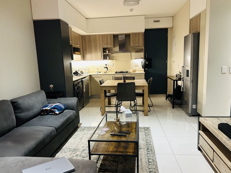 Modern open-plan living area featuring a well-appointed kitchen with built-in cabinetry, integrated appliances, and sleek tiled flooring throughout the space.
