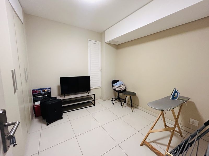 A bedroom featuring tiled flooring, built-in cupboards, and a shutter window, providing a clean and functional space.