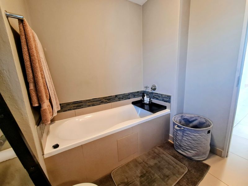 A clean bathroom featuring a built-in bathtub with tiled surround and a decorative mosaic tile accent strip.