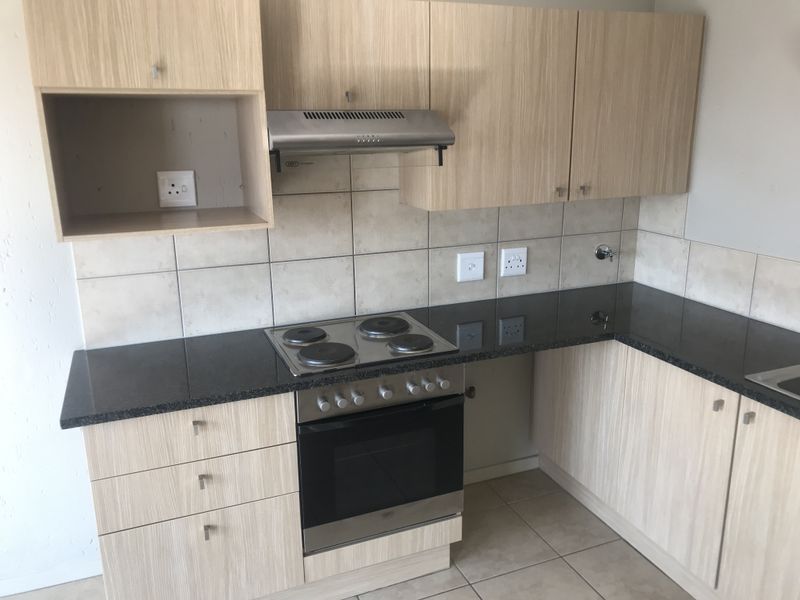 A functional kitchen featuring light wood-grain cabinetry, dark granite countertops, a built-in electric stove and oven, and a tiled backsplash.