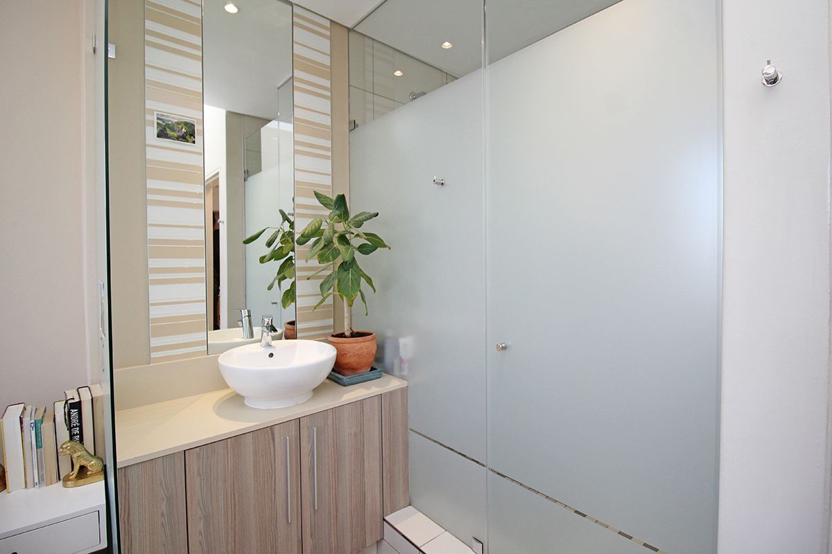 Modern bathroom featuring a vessel sink vanity with wood-finish cabinetry, a large mirror, and a spacious walk-in shower with frosted glass enclosure.