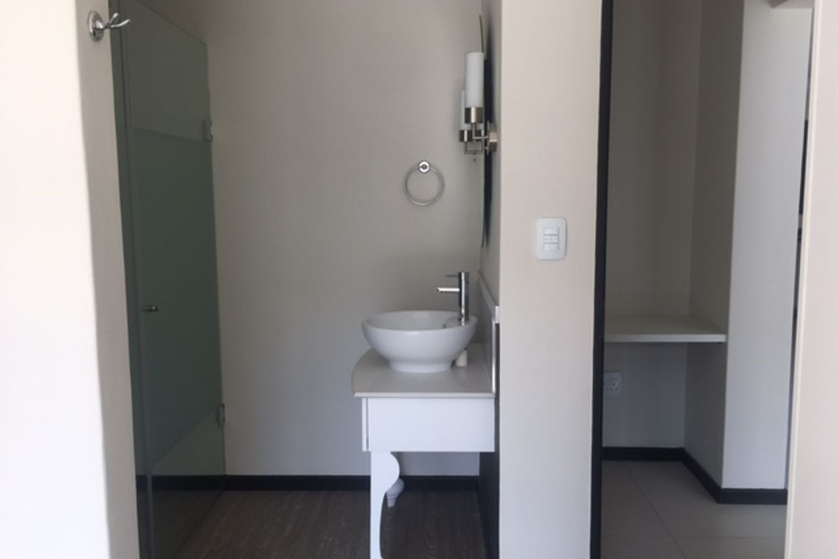A modern bathroom featuring a vessel sink vanity, wall-mounted lighting, and a glass-enclosed shower area with neutral finishes.