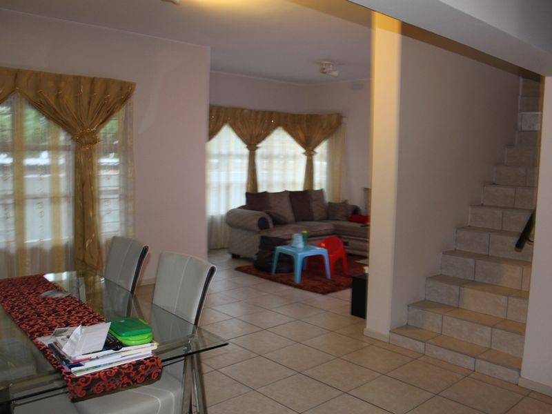 Open plan living and dining area featuring tiled flooring and a staircase leading to the upper level.