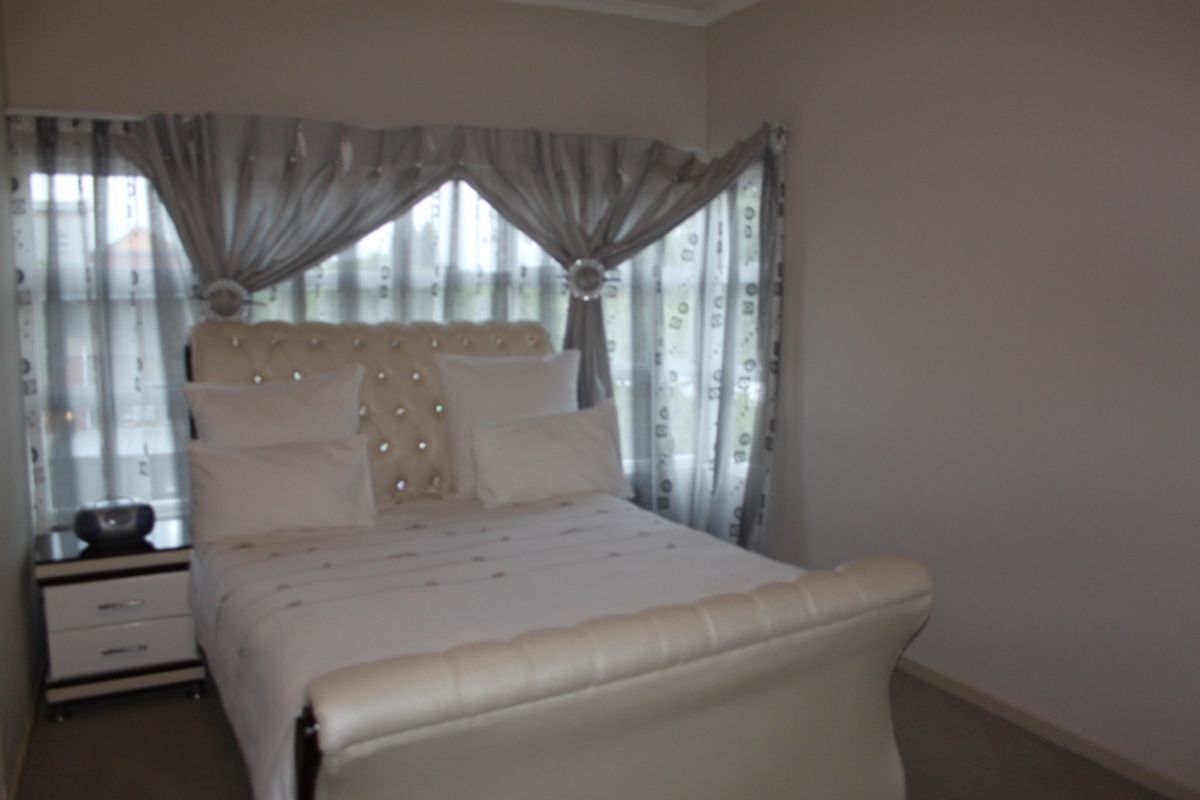 A bedroom featuring carpeted flooring and a window with curtain treatments.