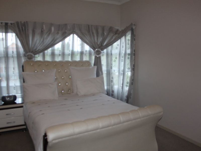 A bedroom featuring carpeted flooring and a window with curtain treatments.