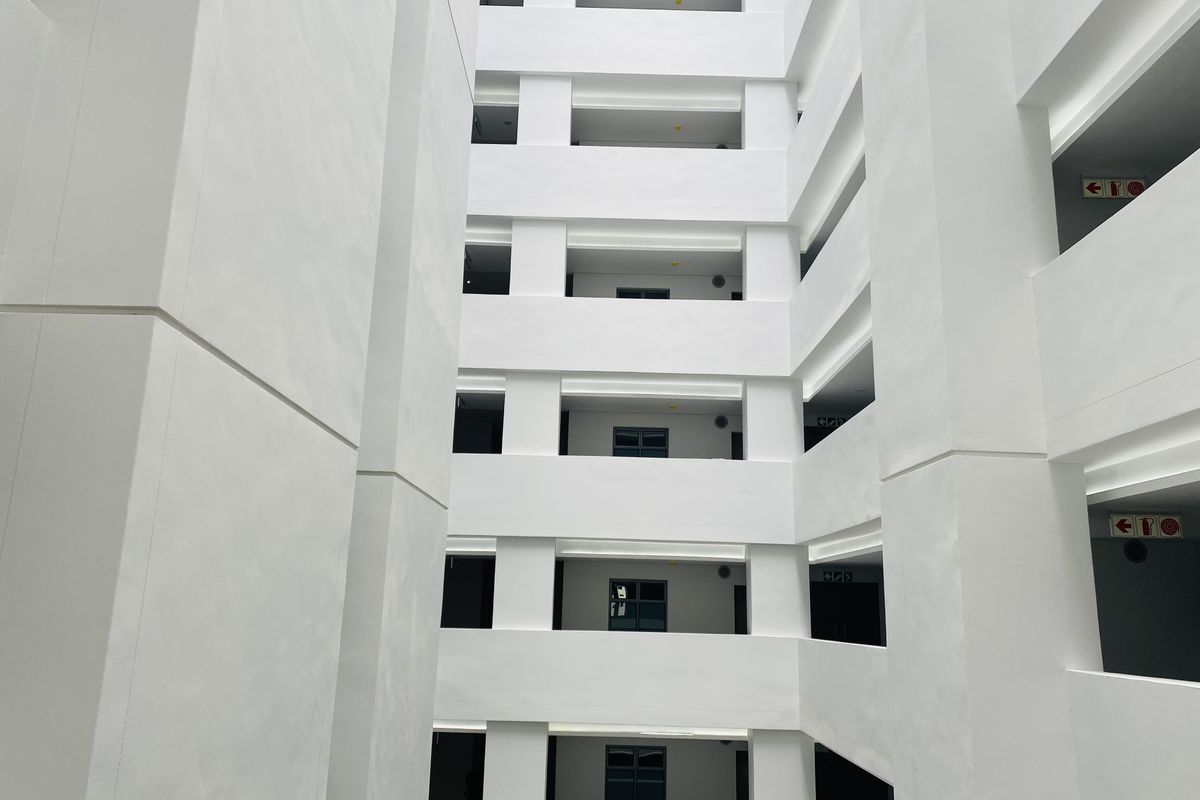 A view of the apartment building's central atrium and exterior corridor structure, featuring clean white finishes and multiple levels of access.