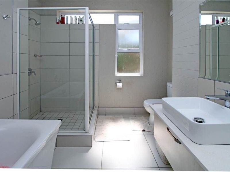 A well-maintained bathroom featuring a separate shower enclosure, bathtub, modern vanity basin, and toilet with neutral tiled finishes.