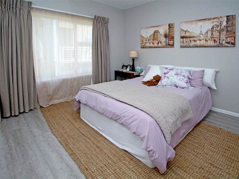 A well-maintained bedroom featuring modern laminate flooring and neutral wall tones, offering a comfortable and functional living space.