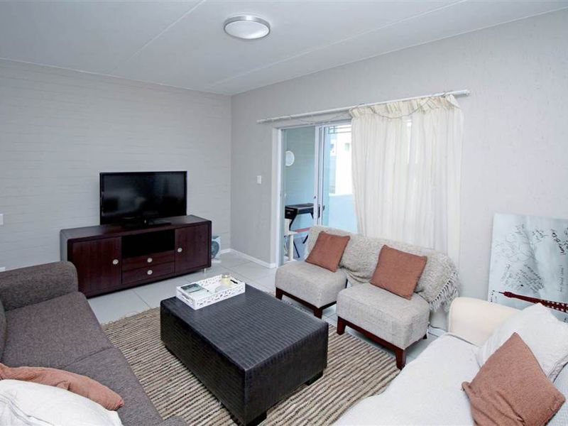 A living room featuring tiled flooring and a sliding glass door providing access to an outdoor area.