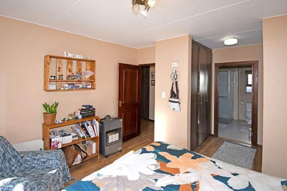 A bedroom featuring built-in wooden wardrobes and direct access to an en-suite bathroom.