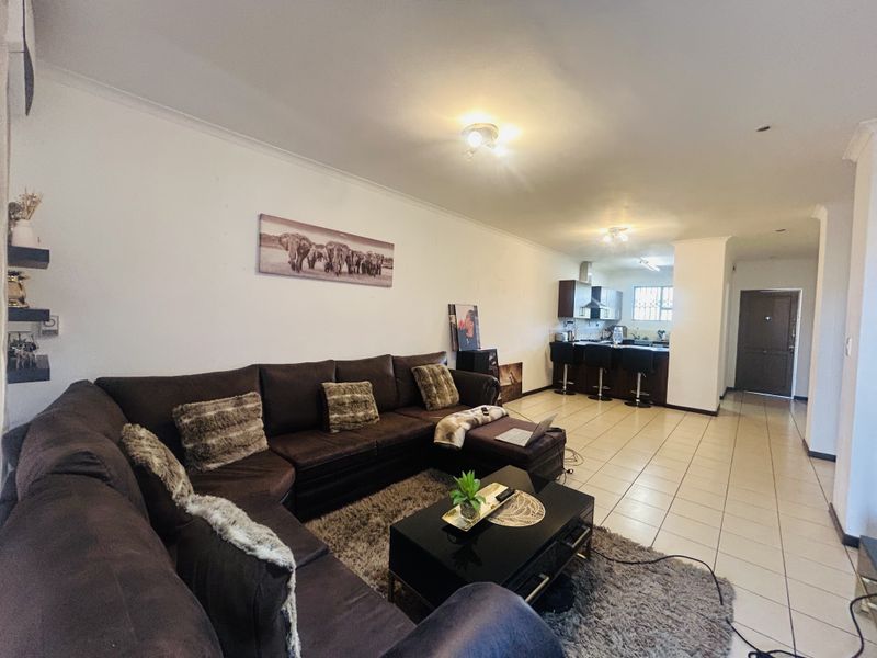 Open-plan living area featuring tiled flooring, a kitchen with breakfast counter, and direct access to the entrance.