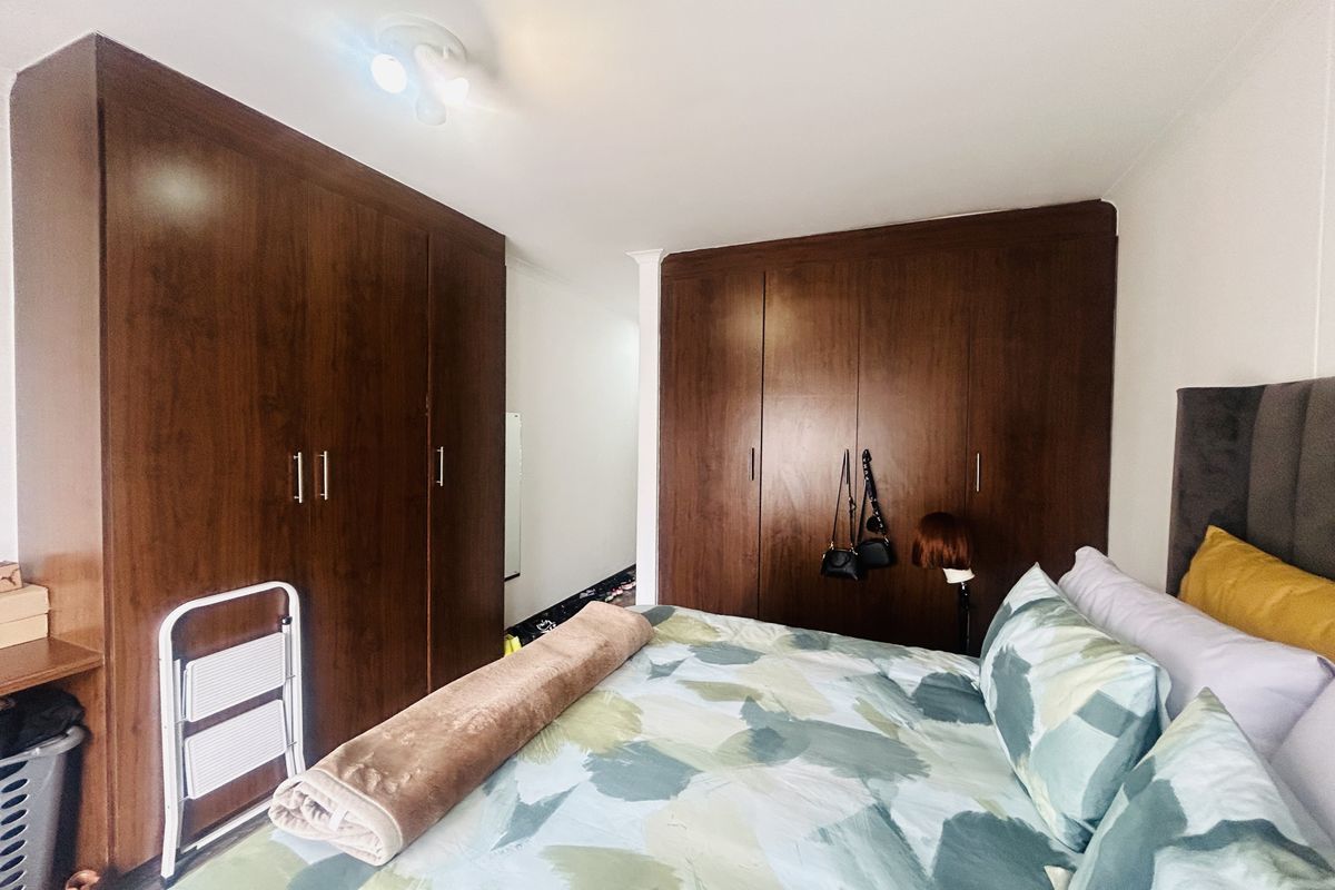 A bedroom featuring extensive dark wood built-in cupboards providing ample storage space.