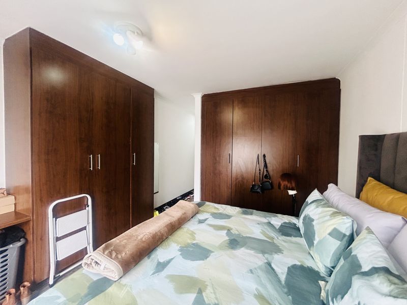A bedroom featuring extensive dark wood built-in cupboards providing ample storage space.