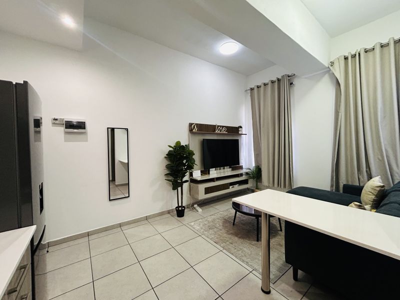 An open-plan living area featuring tiled flooring, recessed lighting, and a built-in media console, creating a functional and well-lit space.