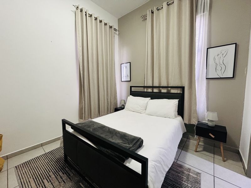 A well-lit bedroom featuring tiled flooring and dual window treatments, providing a comfortable and functional sleeping space.