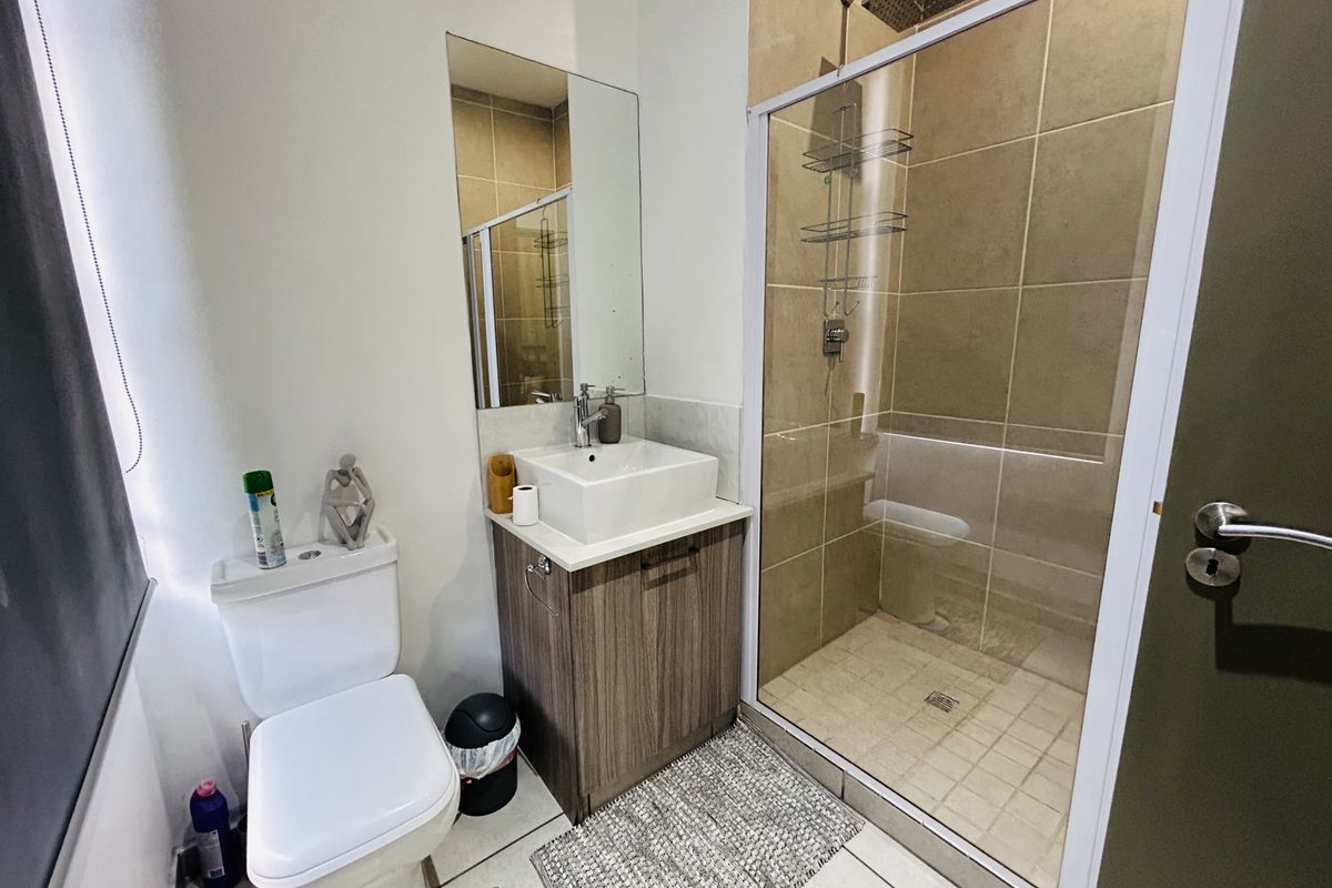 A compact modern bathroom featuring a glass-enclosed shower, a vanity with a vessel sink, and a wall-mounted mirror.