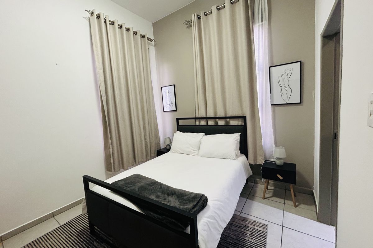 A well-maintained bedroom featuring neutral wall tones, tiled flooring, and dual window treatments, providing a clean and functional living space.