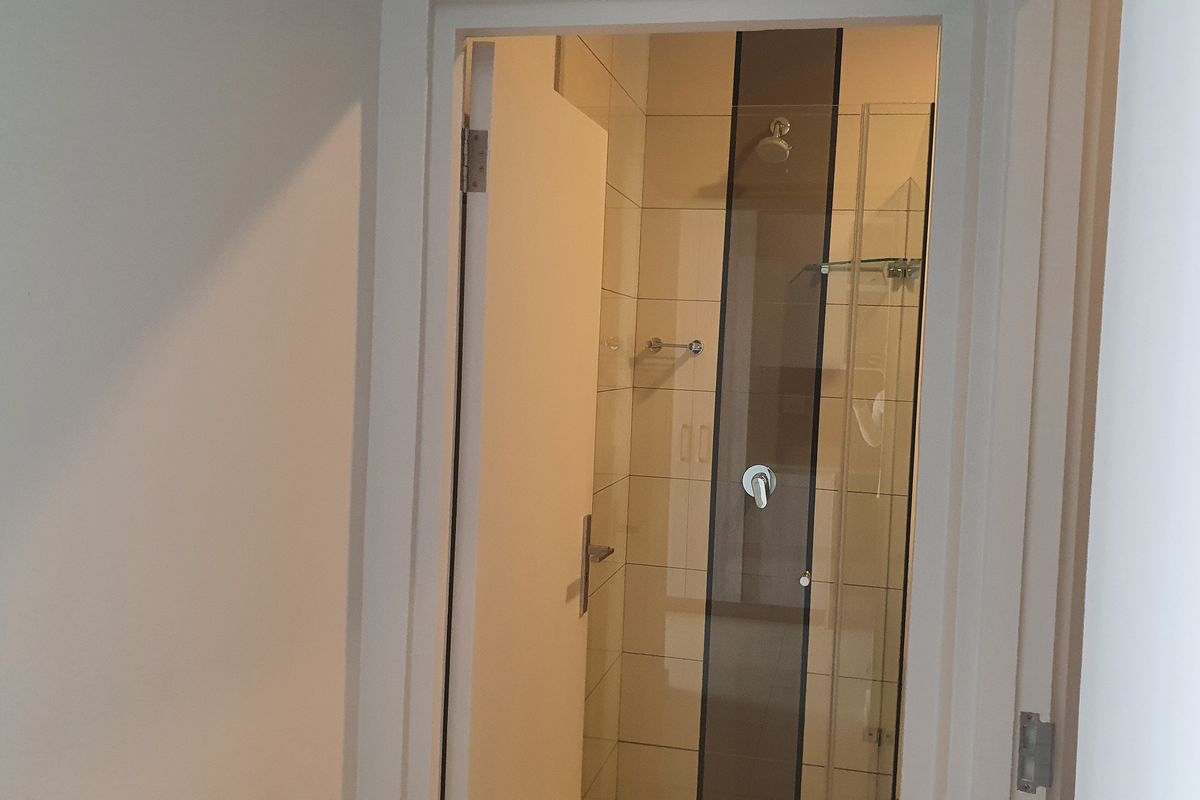 A clean, modern bathroom featuring a glass-enclosed shower with neutral wall tiling and contemporary fixtures.