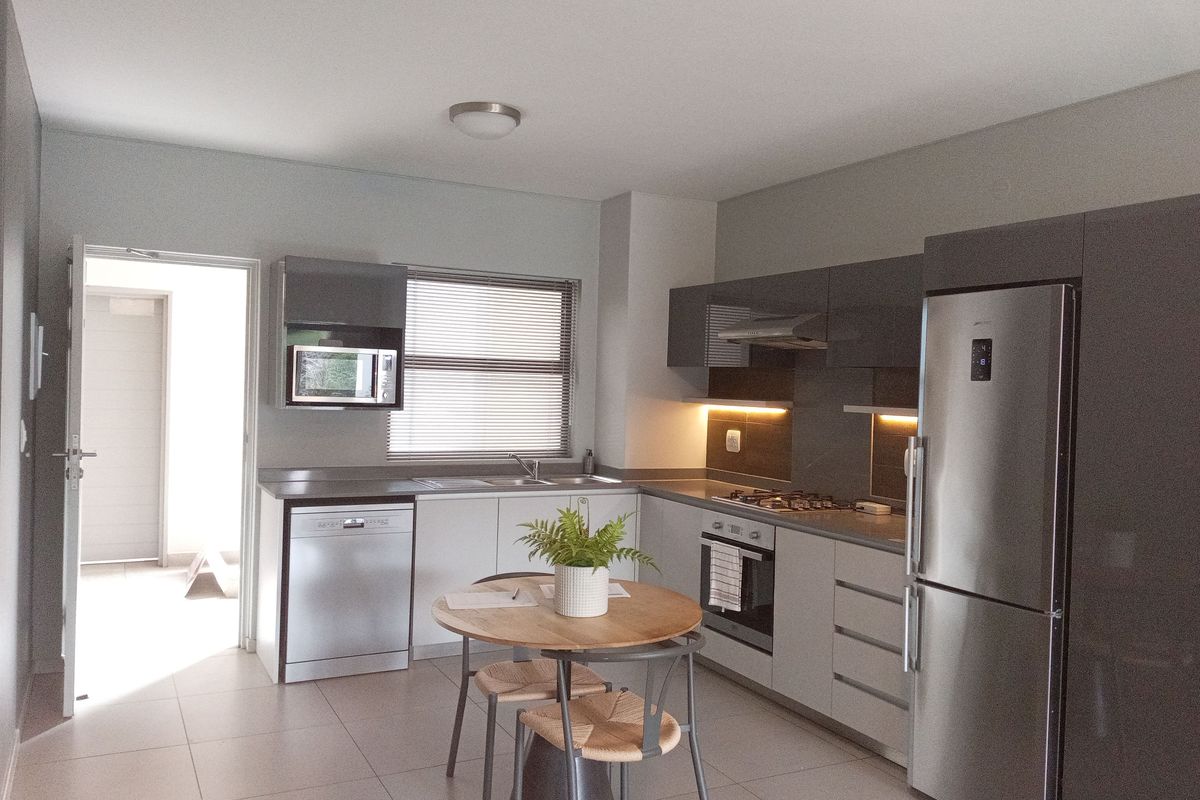 Modern kitchen featuring sleek grey cabinetry, stainless steel appliances, gas hob, integrated dishwasher, and tiled flooring with convenient access to an adjacent hallway.