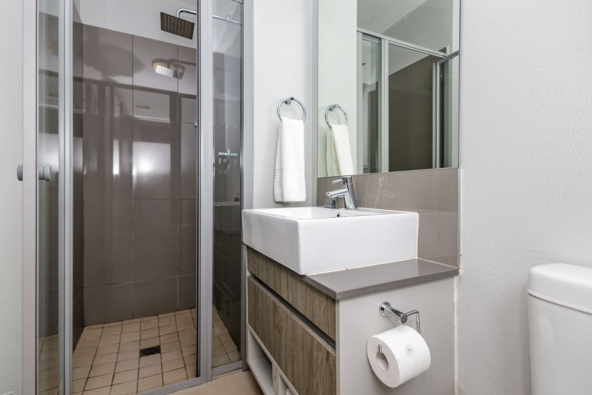 Modern bathroom featuring a glass-enclosed shower, contemporary vanity with a vessel sink, and wall-mounted mirror.