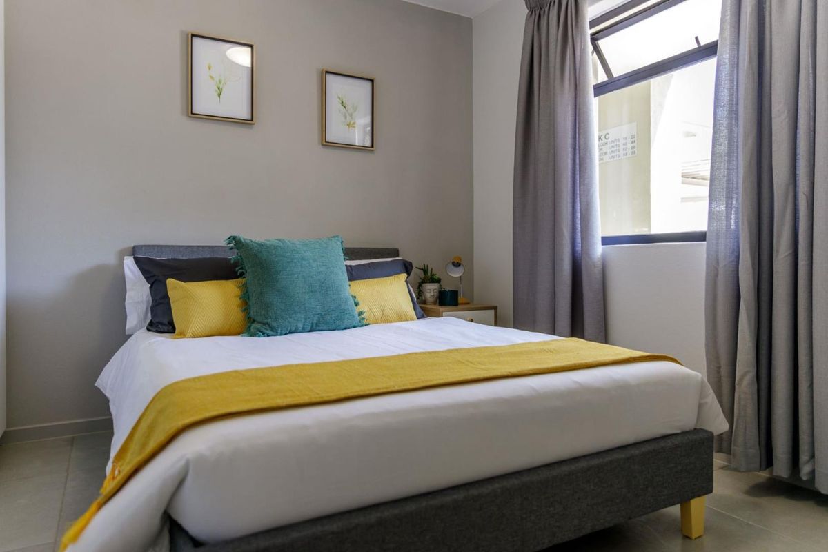 A well-maintained bedroom featuring neutral wall tones, tiled flooring, and a window with curtain tracks.