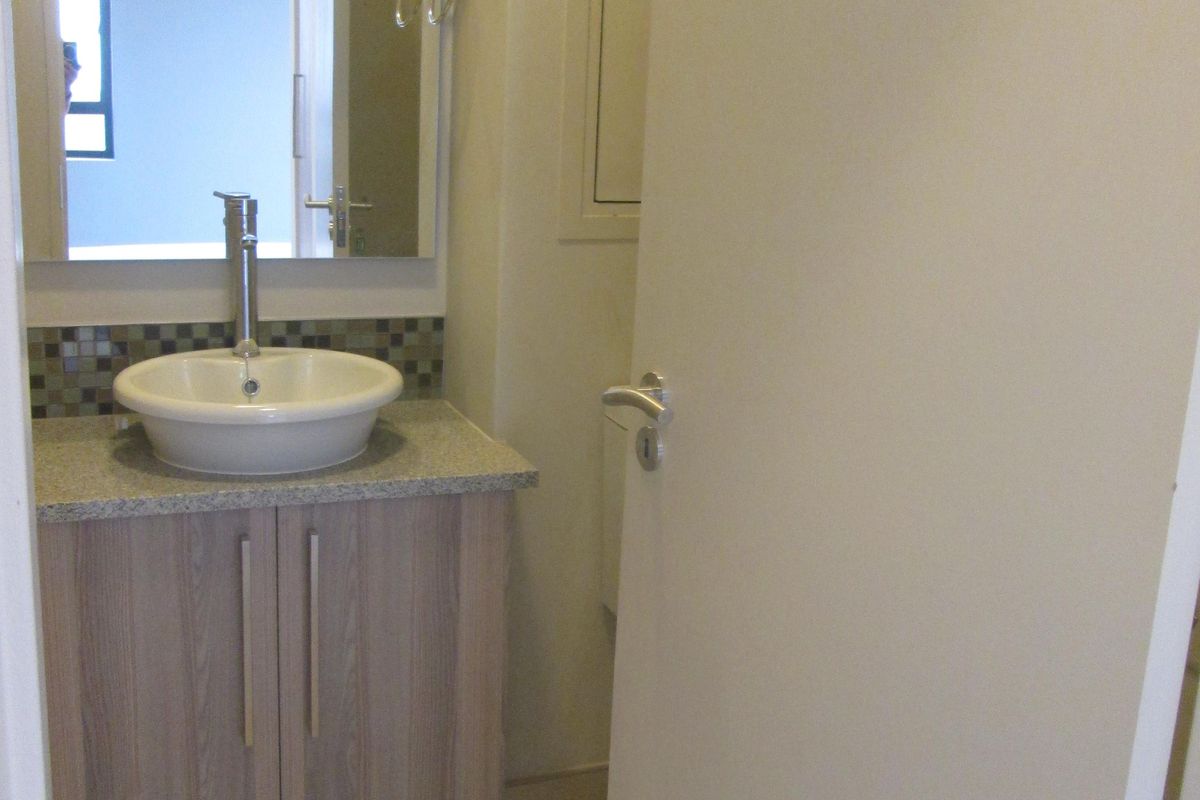 A compact bathroom featuring a modern vessel sink, stone countertop vanity, and tiled backsplash, presenting a clean and functional space.