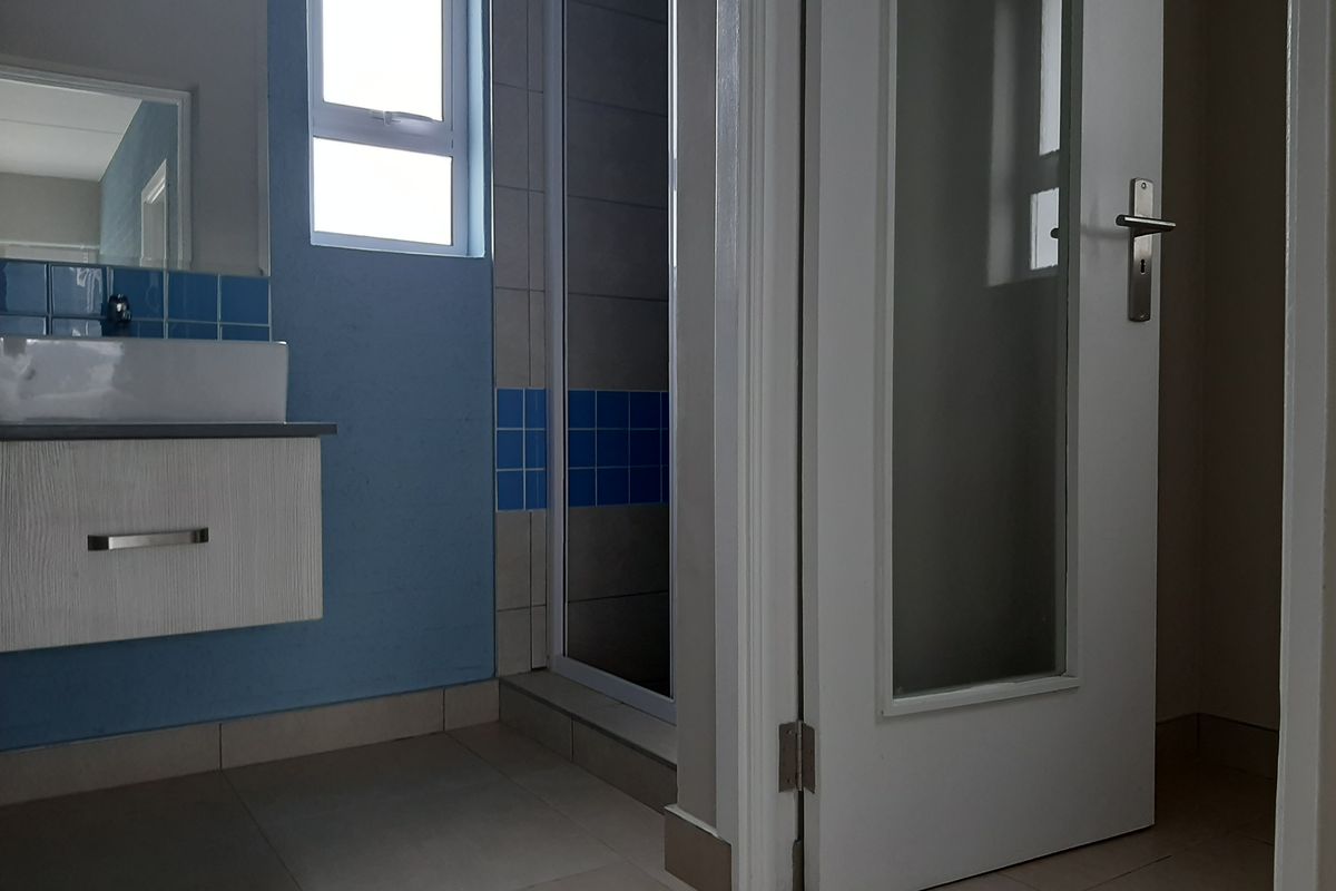 A functional bathroom featuring a floating vanity with a vessel sink, a shower enclosure, and tiled accents, offering a clean and practical layout.