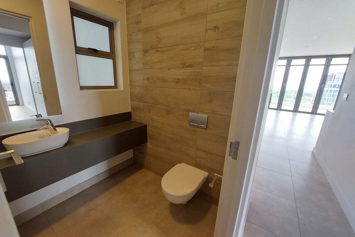 Modern bathroom featuring a wall-mounted toilet, floating vanity with a vessel sink, and stylish wood-look tile accents.