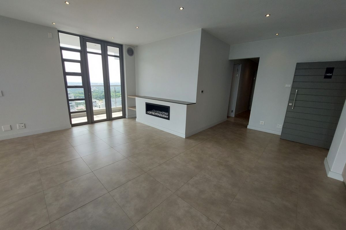 Spacious, modern living area featuring large format floor tiles, a built-in fireplace, recessed lighting, and access to a balcony with expansive views.