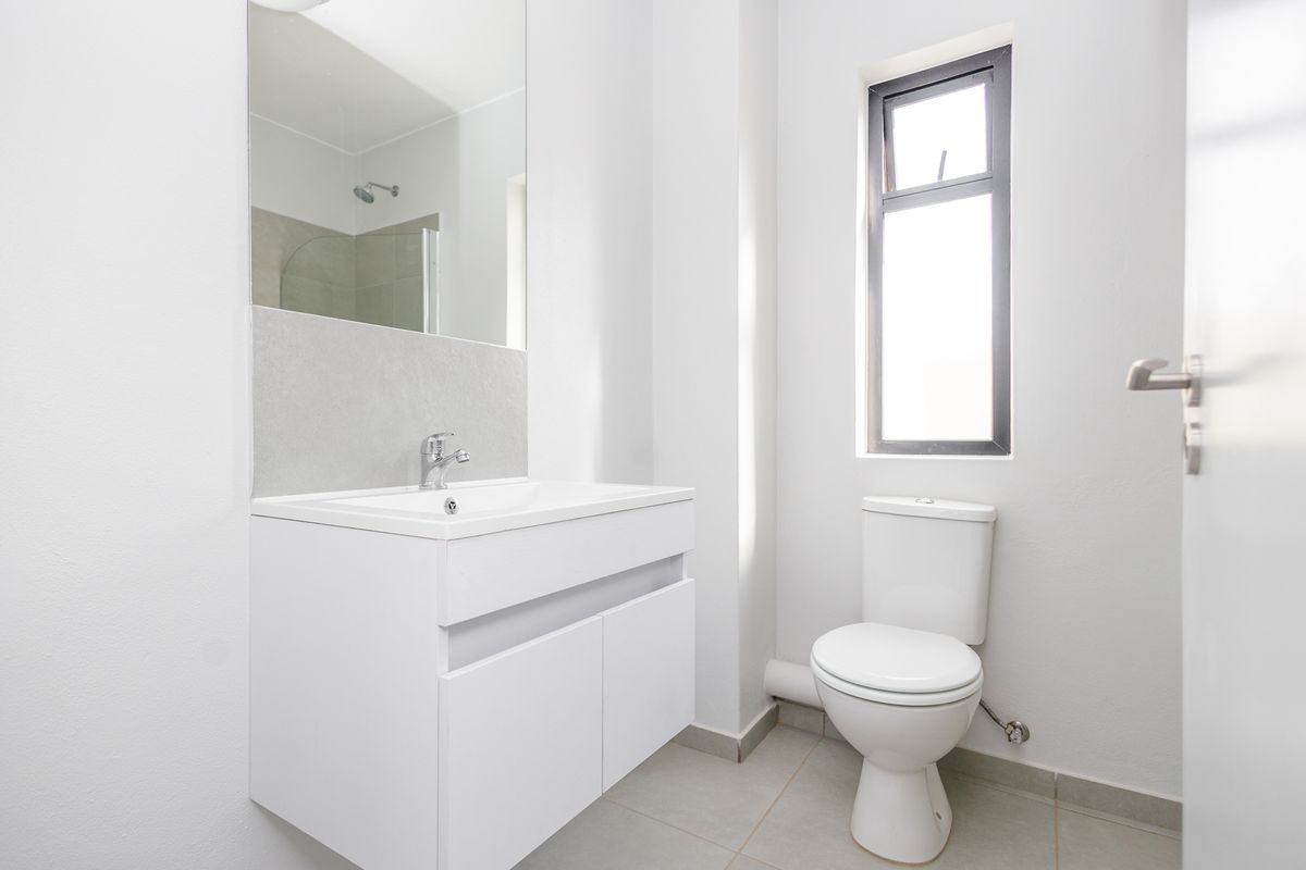 A clean, modern bathroom featuring a wall-mounted vanity with a basin, a toilet, and a shower enclosure with a glass door.