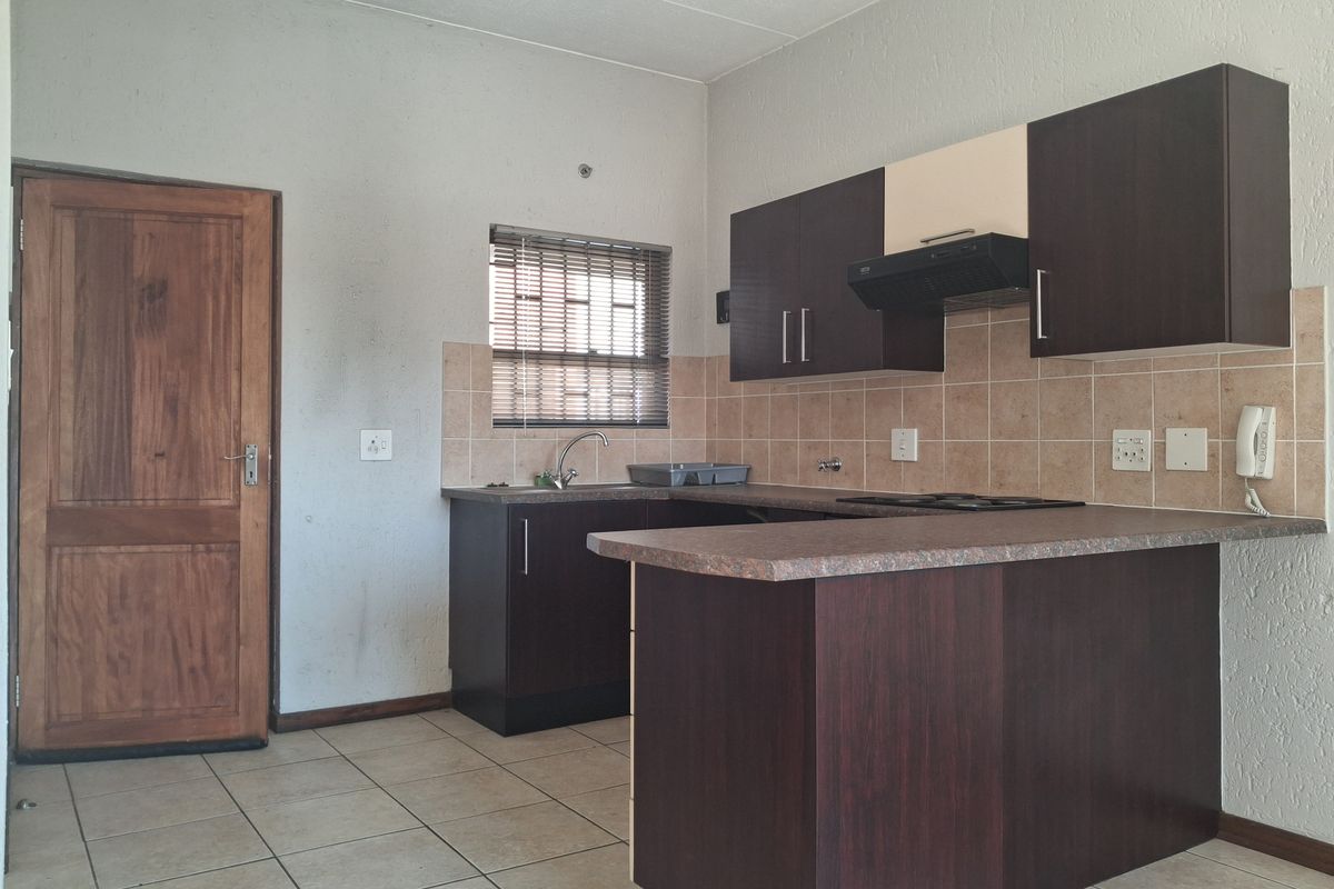 A functional kitchen featuring dark cabinetry, laminate countertops, tiled backsplash, and ceramic flooring, offering a practical layout for daily use.