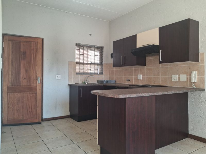 A functional kitchen featuring dark cabinetry, laminate countertops, tiled backsplash, and ceramic flooring, offering a practical layout for daily use.