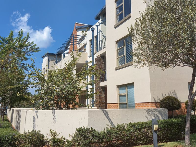 A modern multi-story apartment building facade featuring stone cladding, plastered walls, and private balconies with integrated pergola structures.