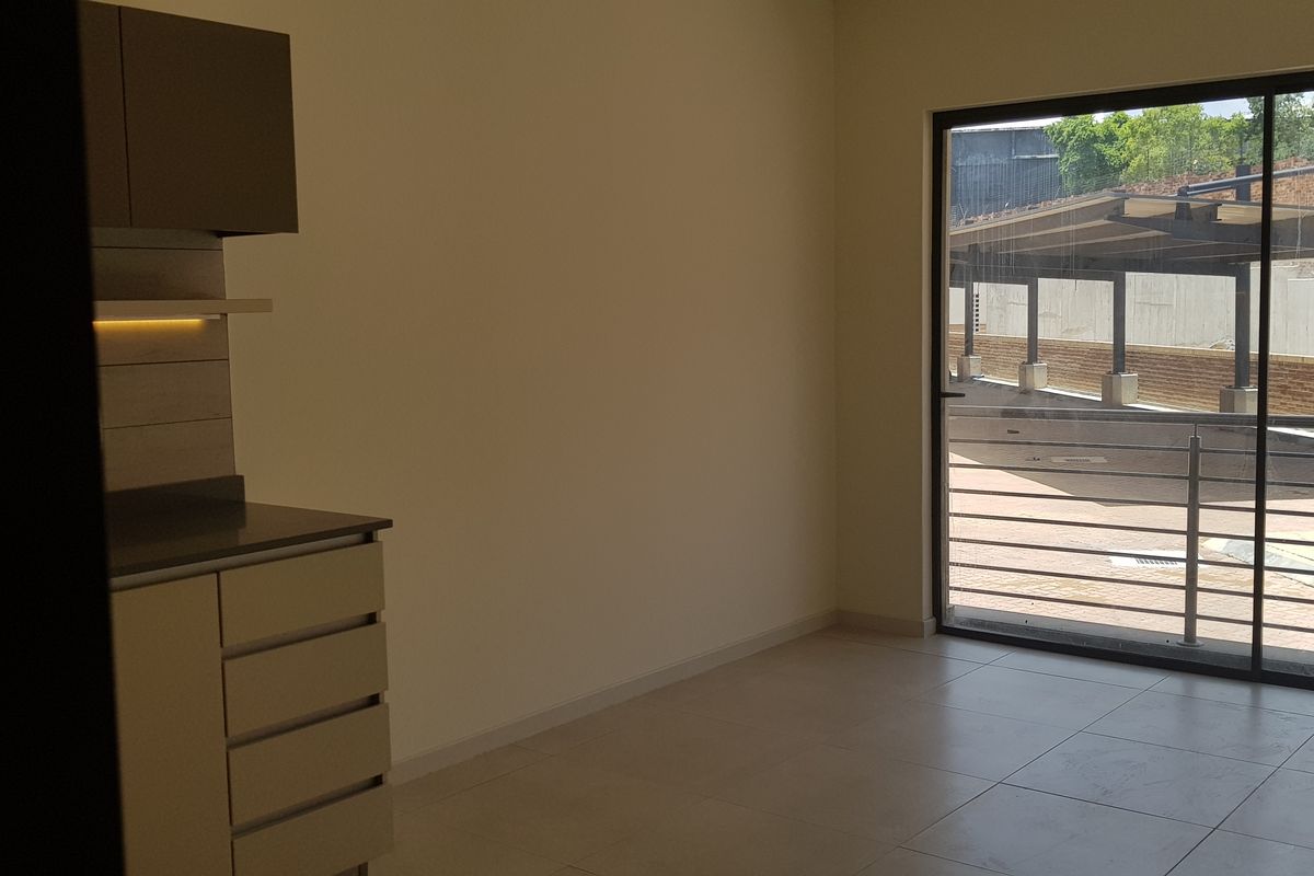 An empty open-plan living area featuring modern built-in cabinetry, tiled flooring, and a large sliding glass door leading to an outdoor space.