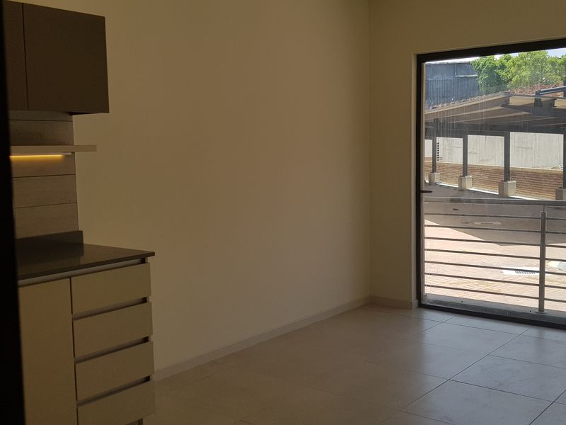 An empty open-plan living area featuring modern built-in cabinetry, tiled flooring, and a large sliding glass door leading to an outdoor space.