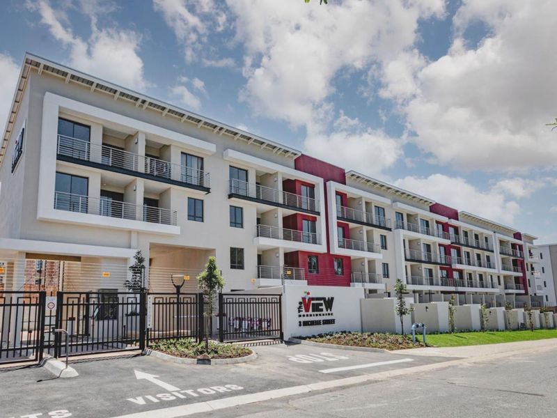 Modern multi-story apartment complex exterior featuring private balconies, secure gated entrance, and designated visitor parking area.