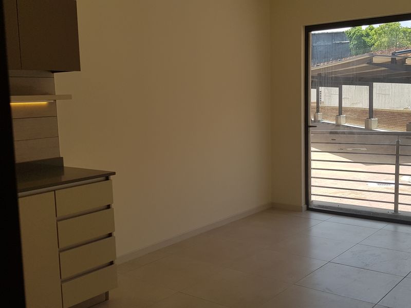 An open-plan living area featuring modern built-in cabinetry, tiled flooring, and a large sliding glass door providing access to the exterior.