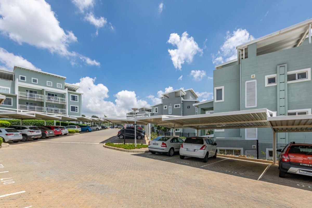 Exterior view of a modern apartment complex featuring paved driveway areas and covered parking bays for residents.
