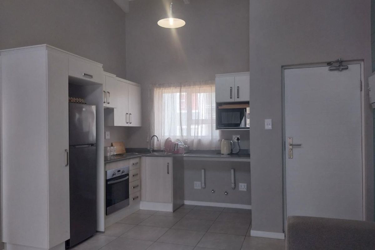 A functional kitchen featuring white cabinetry, built-in oven, tiled flooring, and a dedicated space for appliances under the counter.