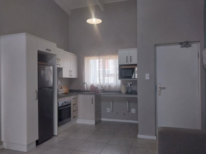 A functional kitchen featuring white cabinetry, built-in oven, tiled flooring, and a dedicated space for appliances under the counter.
