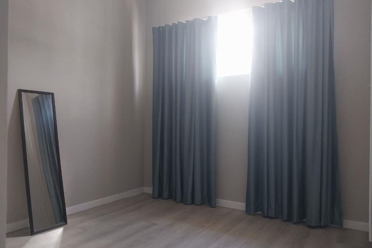 A bright, empty bedroom featuring neutral wall tones and modern laminate flooring, ready for personalization.