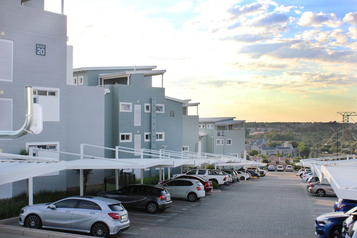 Exterior view of a modern apartment complex featuring paved parking areas with covered carports and multi-story residential blocks.
