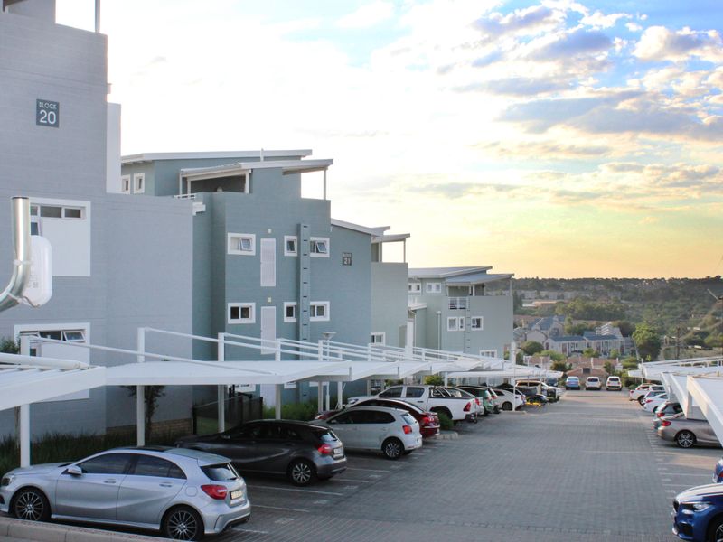 Exterior view of a modern apartment complex featuring paved parking areas with covered carports and multi-story residential blocks.