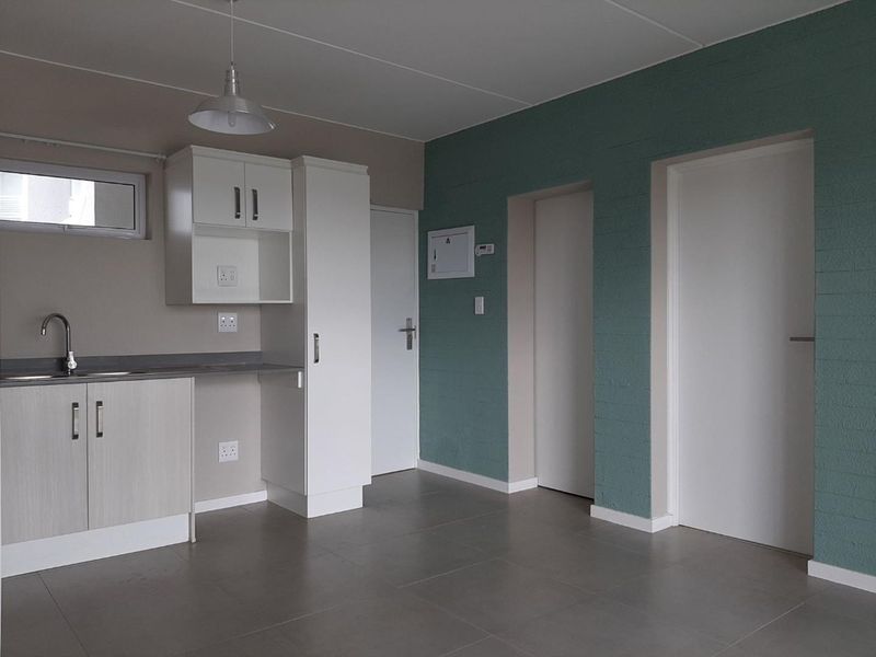 A clean, modern kitchen area featuring neutral cabinetry, a stainless steel sink, and tiled flooring, offering a functional and well-maintained space.