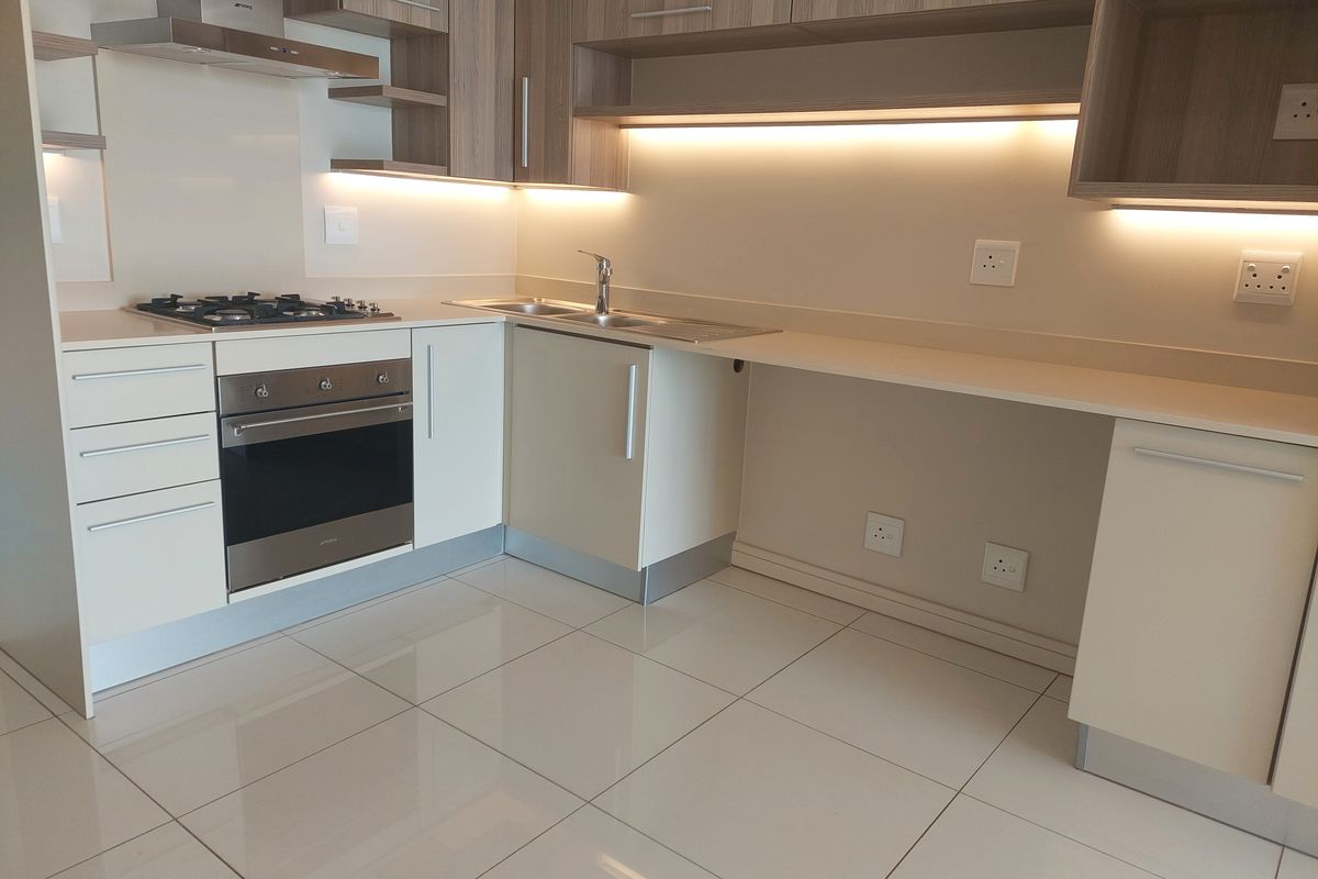 Modern kitchen featuring sleek cabinetry, stone countertops, integrated gas hob, oven, extractor fan, and polished tiled flooring in a clean, contemporary layout.