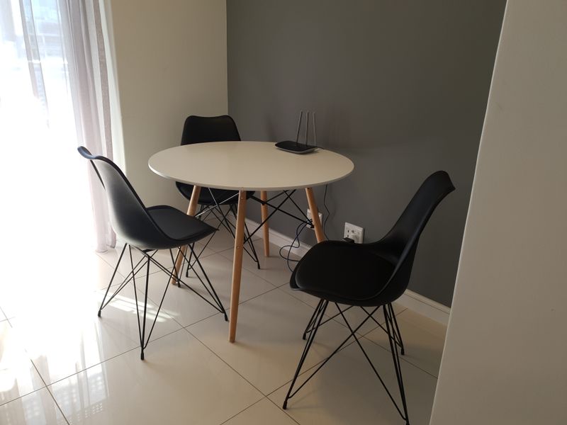 A bright dining area featuring modern tiled flooring and a neutral grey accent wall, providing a clean and functional space.