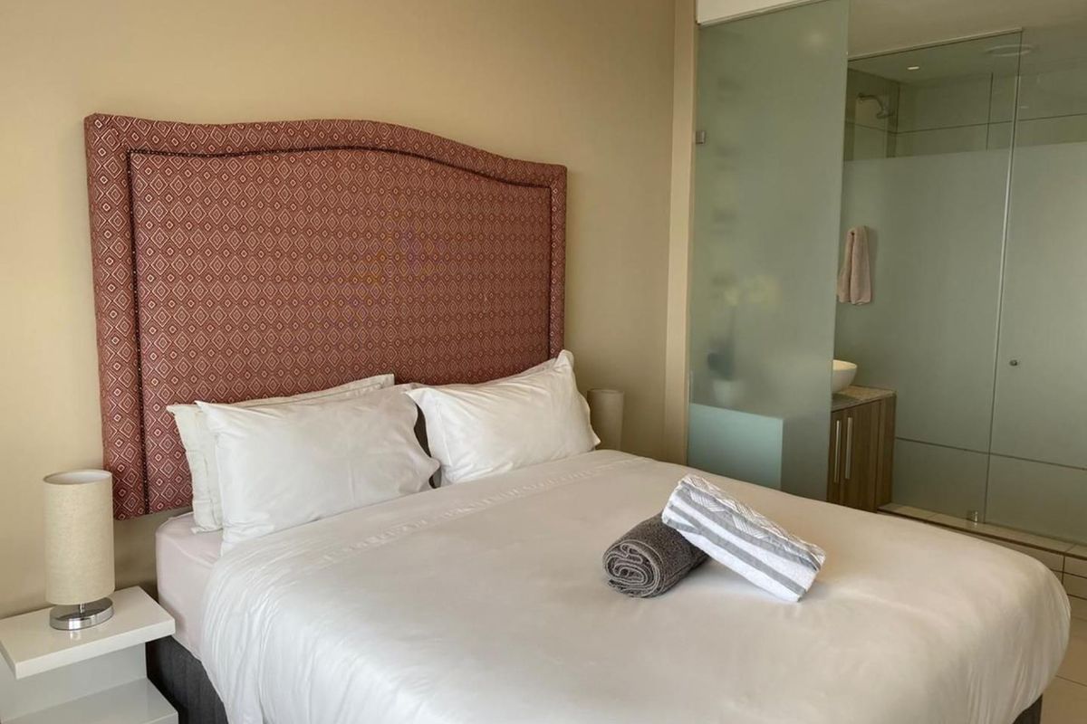 A well-maintained bedroom featuring a modern frosted glass partition that separates the sleeping area from the en-suite bathroom.