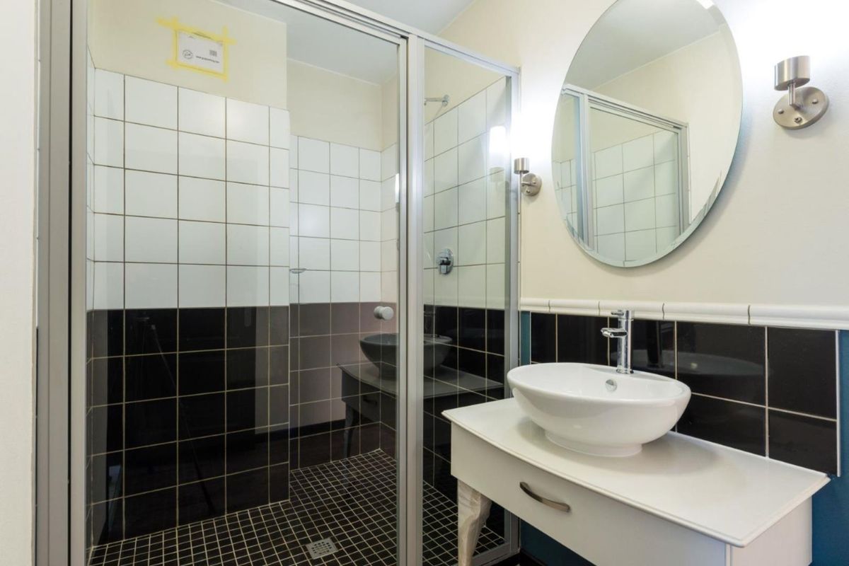 Modern bathroom featuring a glass-enclosed shower, vessel sink vanity, and contrasting black and white tiled walls.